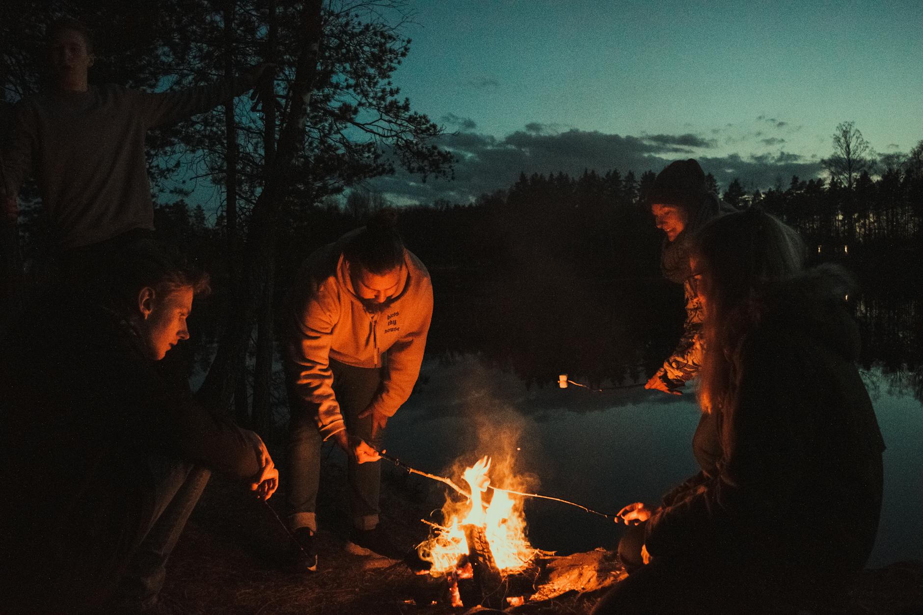 Campfire evening by the lake with friends laughing and relaxing